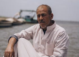Elderly fisherman sitting on a boat by Burullus Lake in Kafr El-Shaikh, Egypt.